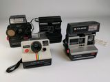 trois appareils photo Polaroid posés les uns sur les autres sur une table
