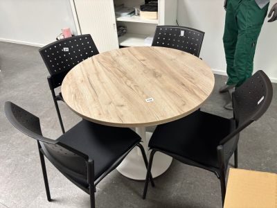 un homme debout dans une pièce où se trouvent une table et des chaises