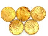 quatre pièces d'or sont empilées les unes sur les autres sur une surface blanche