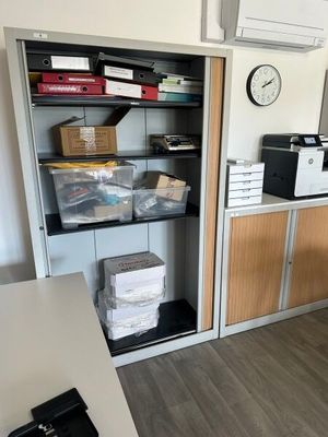 une pièce avec un bureau, des étagères et une horloge accrochée au mur