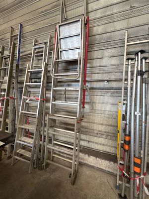 several ladders are lined up against a wall in a warehouse