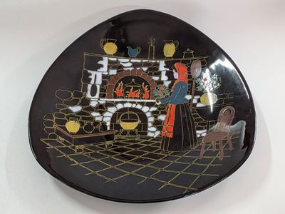 a black plate with a picture of a man and a woman in front of a fireplace