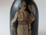 un vase noir sur lequel figure l'image d'un homme tenant une fleur