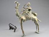 bronze statue of a man riding a camel with a bird on his back