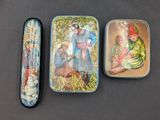 three tins with different designs on them sitting on a table