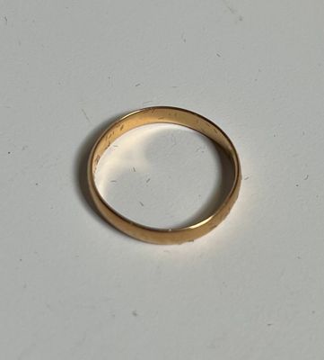 une bague en or posée sur une surface blanche