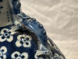 a blue and white vase with a frog sitting on top of it