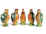 quatre figurines en céramique représentant des coqs sont alignées sur une surface blanche