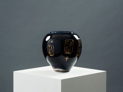 un vase noir posé sur un socle blanc