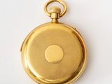 a close up of a gold pocket watch on a white surface