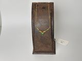 un collier en or orné de pierres vertes, posé sur un socle en bois