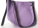 purple handbag on a white surface with a black strap