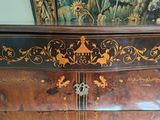 a wooden cabinet with a painting on the wall behind it