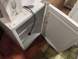 a small white refrigerator with its door open on the floor
