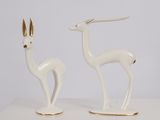 une paire de figurines de cerfs blanches et dorées posées sur une table blanche
