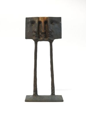 un gros plan d'une sculpture représentant deux visages, posée sur un socle