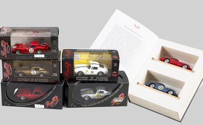 Plusieurs petites voitures sont rangées dans des boîtes posées sur une table, à côté d'un livre