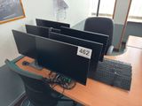 three computer monitors sitting on a desk with a keyboard and mouse