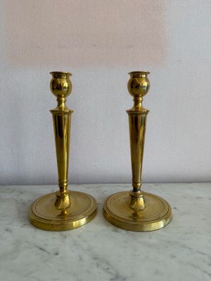 une paire de bougeoirs en laiton posés sur une table en marbre, surmontés d'un abat-jour rose