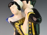 a figurine of a man holding a hat on his head