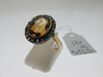 une image représentant une bague ornée d'une grosse pierre facettée entourée de diamants noirs