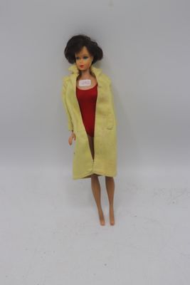 poupée Barbie portant un manteau jaune et une robe rouge, aux cheveux noirs