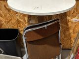 a small table with a chair and a trash can in the corner