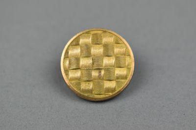 un gros plan d'un bouton doré sur une surface grise