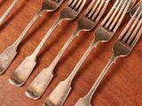 several forks and spoons on a wooden table with a knife and fork