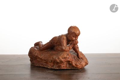 statue d'un garçon allongé sur un rocher, posée sur une table en bois