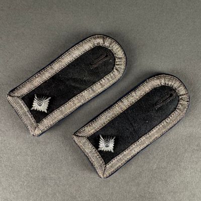 pair of black and silver embroidered badges on a gray surface