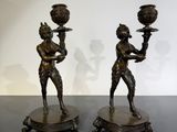 pair of bronze figurines of a man and a woman holding candles