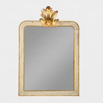 a gold framed mirror on a white wall with a gold leaf decoration