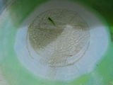 a green and white bowl sitting on a wooden table