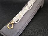 Gros plan sur un collier de perles blanches avec un fermoir en or
