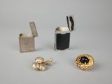 deux paires de boucles d'oreilles et un briquet posés sur une surface blanche