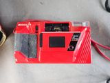 a red camera sitting on top of a table next to a pair of shoes