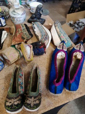 Plusieurs paires de chaussures sont posées sur une table dans une pièce encombrée.