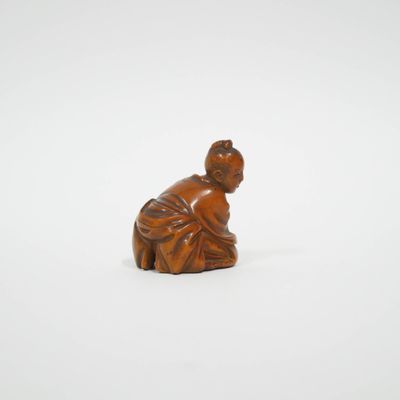 une petite figurine en bois représentant une femme agenouillée par terre