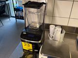 un mixeur posé sur le plan de travail de la cuisine, à côté d'une tasse à café