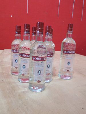 Six bouteilles de vodka Sobbie sont posées sur une table devant un mur rouge.