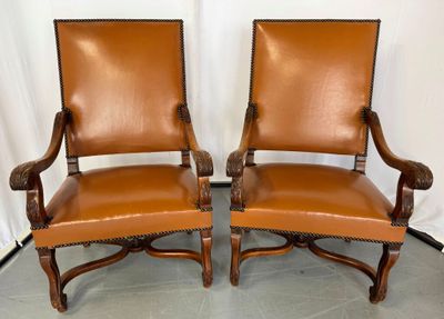 a pair of leather chairs with wooden arms and arms