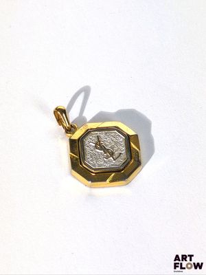 un pendentif en or orné d'une pièce de monnaie, posé sur un fond blanc