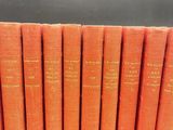 a set of six orange books with gold lettering on them