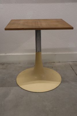 une petite table avec un plateau en bois sur un sol en béton