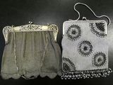 two silver purses sitting on top of a table next to each other
