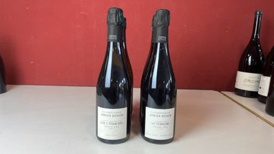 Deux bouteilles de vin sont posées sur un comptoir devant un mur rouge.