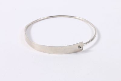 gros plan d'un bracelet en argent sur une surface blanche