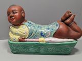 une figurine représentant un bébé allongé sur un plateau vert