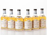 six bouteilles de différentes sortes d'alcool alignées sur une surface blanche